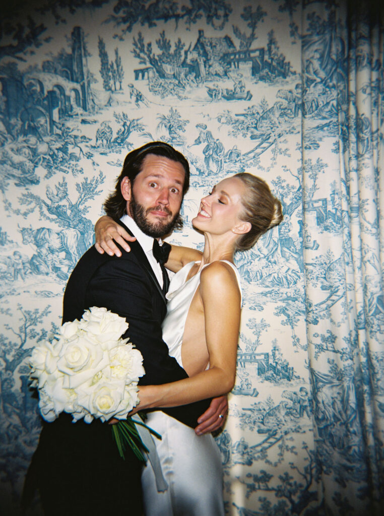 Trsitan and Meredith embracing in front of a blue and white patterned backdrop