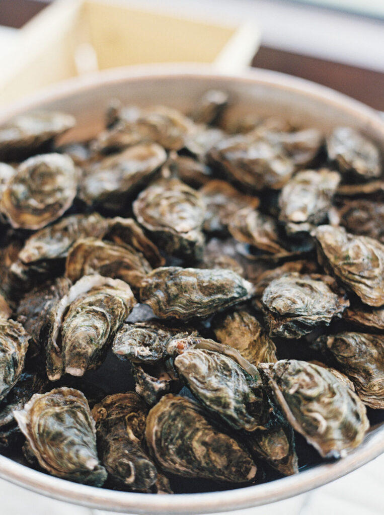 A close-up image of a large bowl filled with unopened oysters