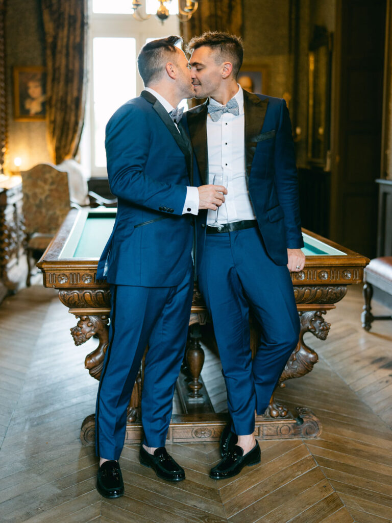 Kevin and Steven share an intimate kiss by a pool table at their wedding venue in France