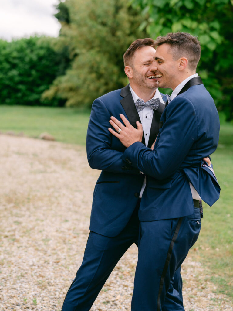 Kevin and Steven laugh and embrace in a joyful moment outside during their wedding celebration