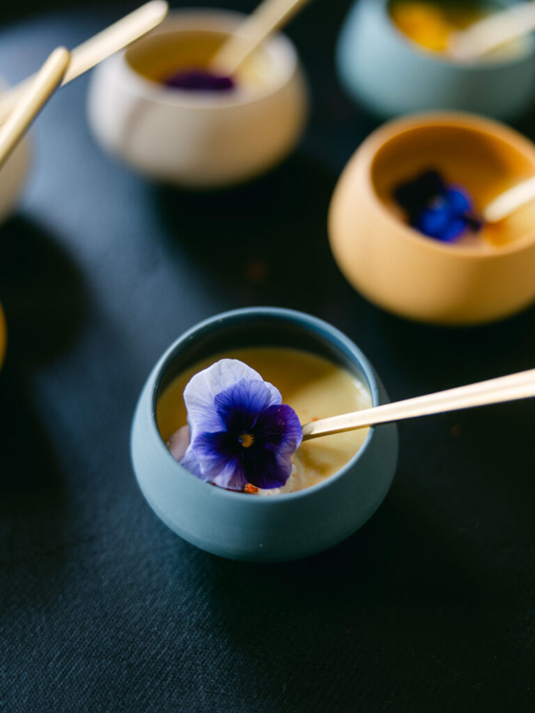 Small bowls of creamy soup garnished with edible flowers at Kevin and Steven's wedding reception in France