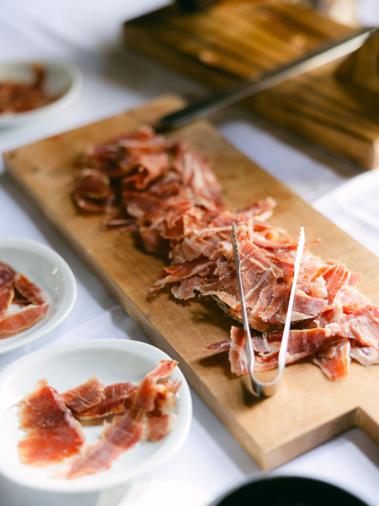 A wooden board displaying thinly sliced cured ham at Kevin and Steven's wedding reception