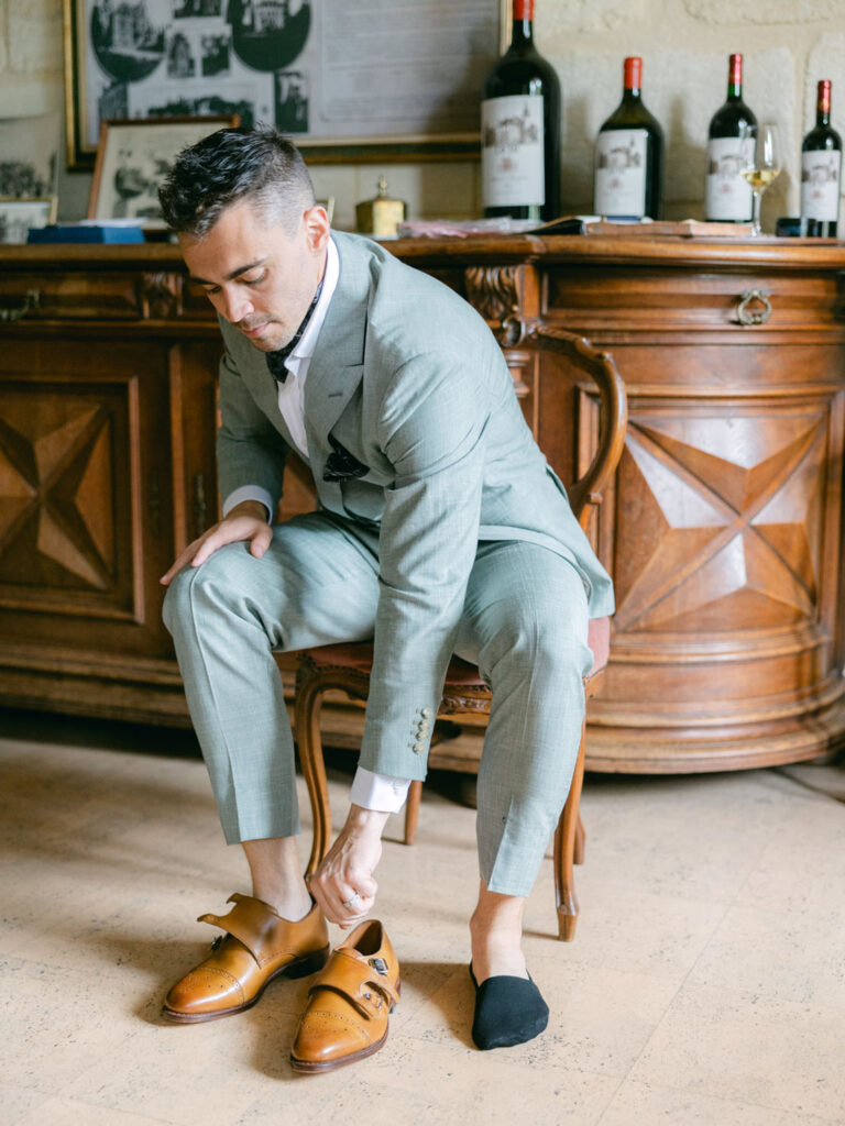 Groom adjusting his shoes while getting ready for their wedding in France