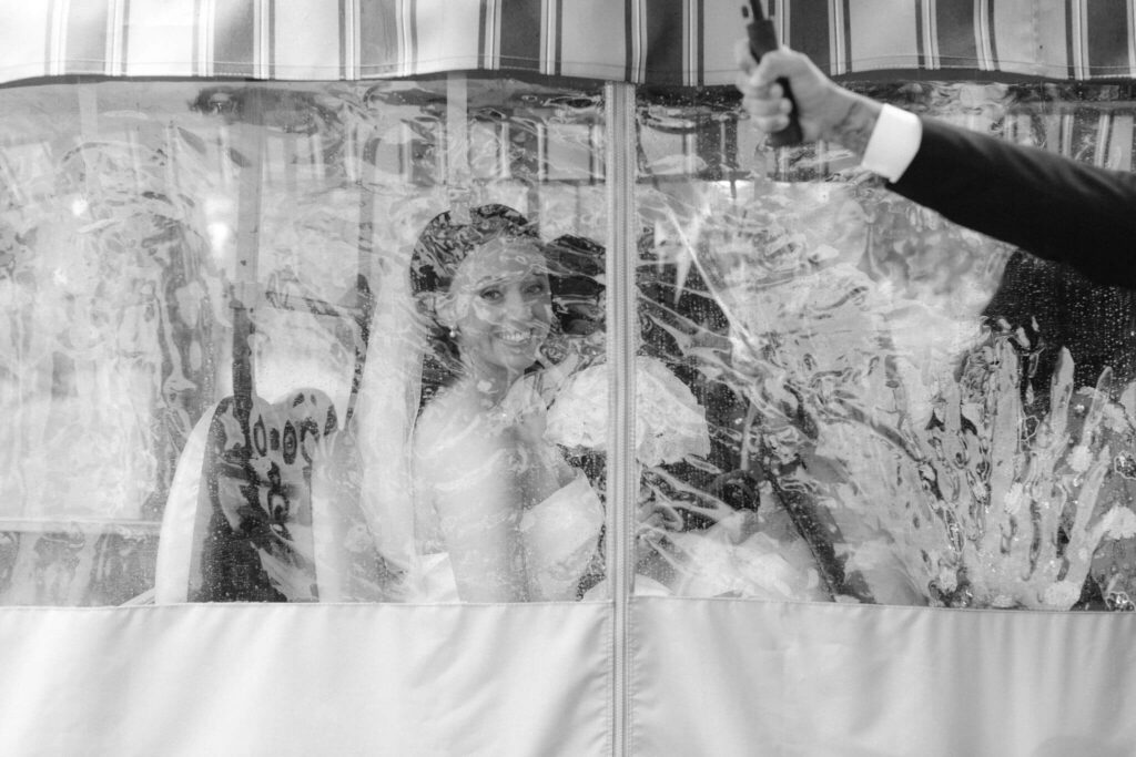 Bride smiling through a rain-soaked covering on her wedding day