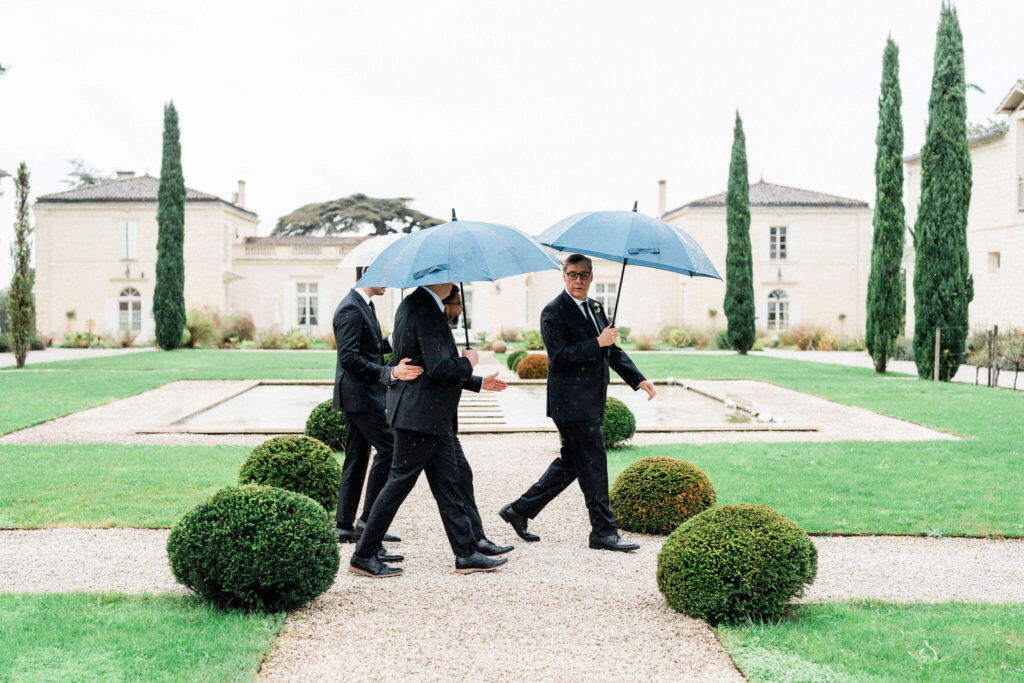 Groomsmen walking with blue umbrellas on a rainy wedding day