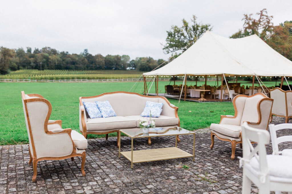 Outdoor lounge setup with a tent in the background for a rainy wedding day