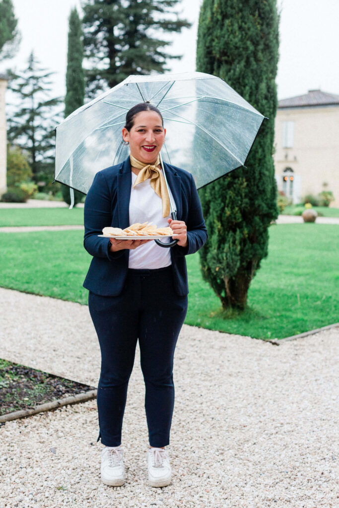 Wedding vendor holding a tray under a clear umbrella on a rainy day