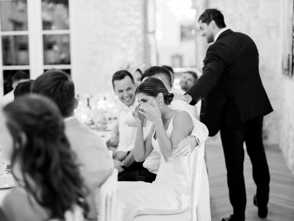 Alexandra, the bride wiping tears of laughter during a heartfelt toast