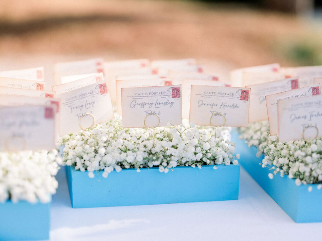 Escort cards styled as vintage postcards displayed in baby's breath arrangements