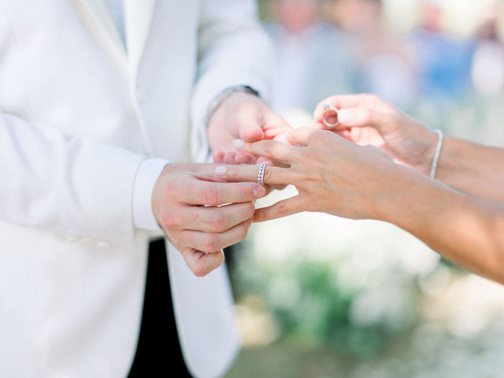 Groom sliding a wedding ring onto the bride’s finger