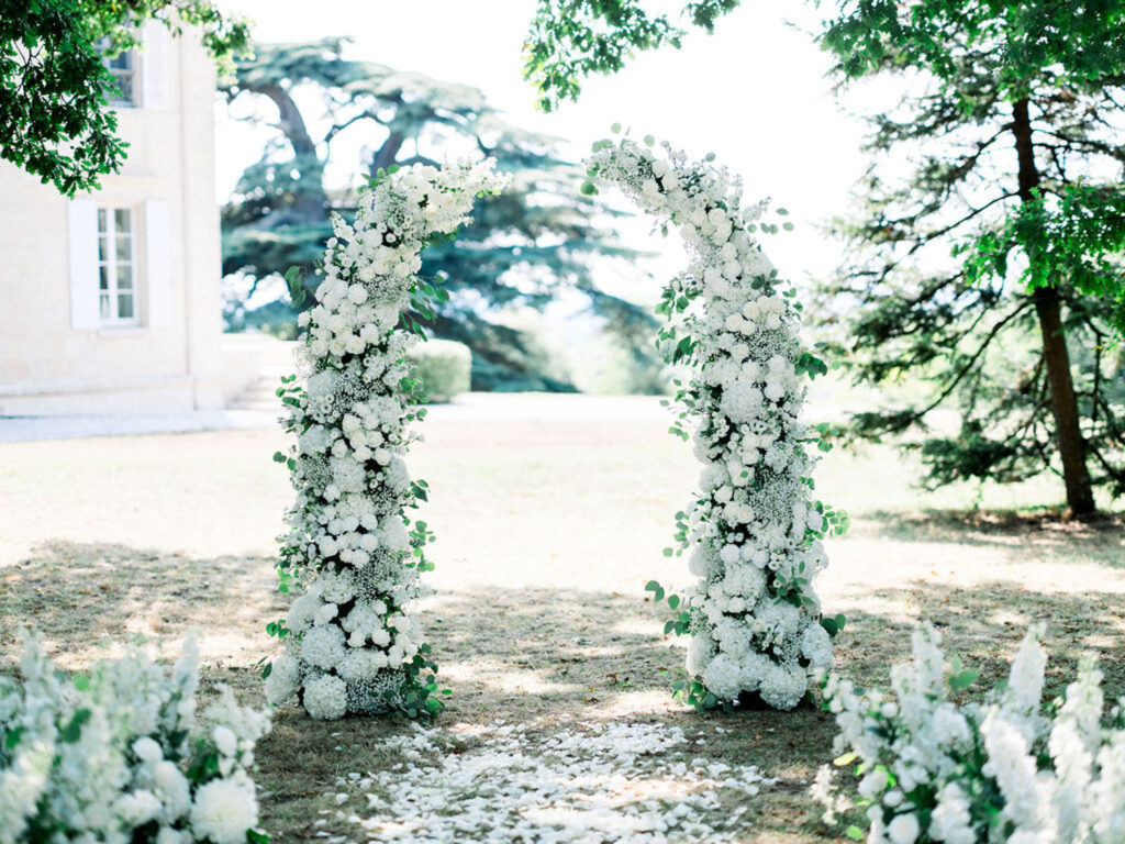 Floral arch filled with white blooms at the ceremony site