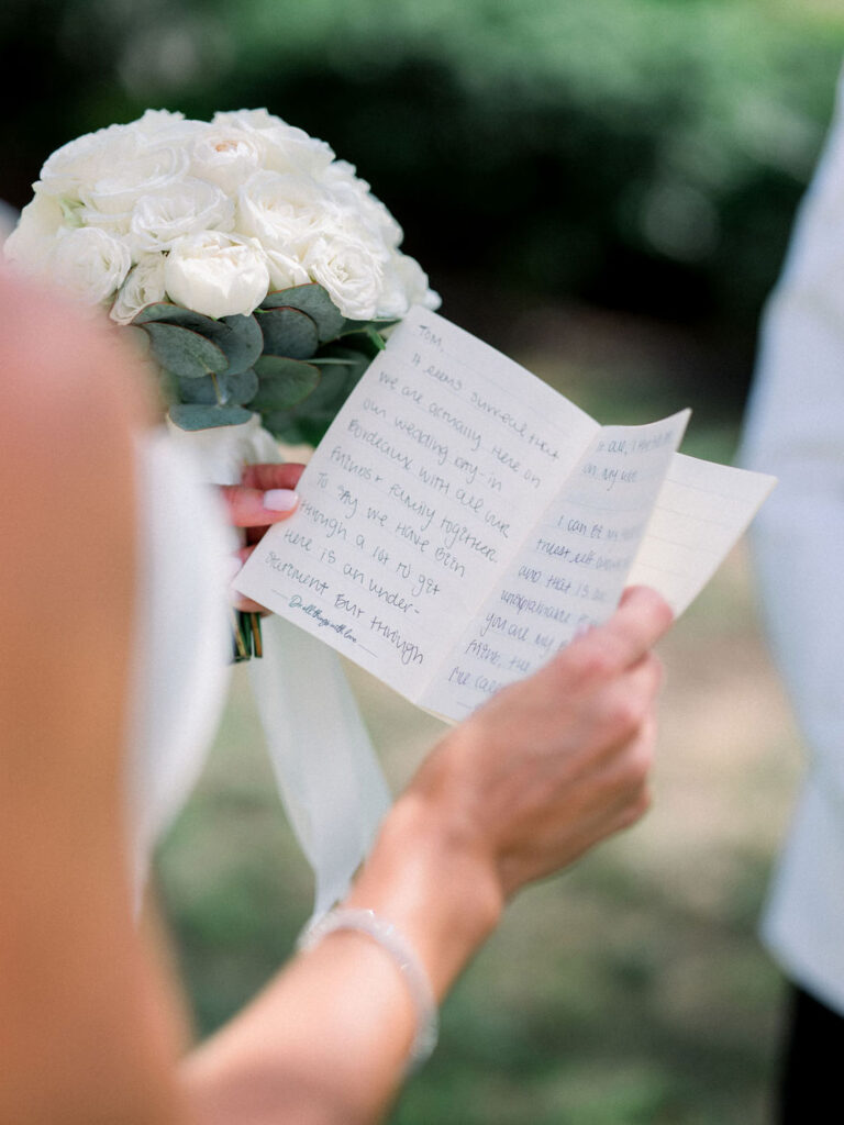 Alexandra, the bride holding a bouquet while reading her wedding vows