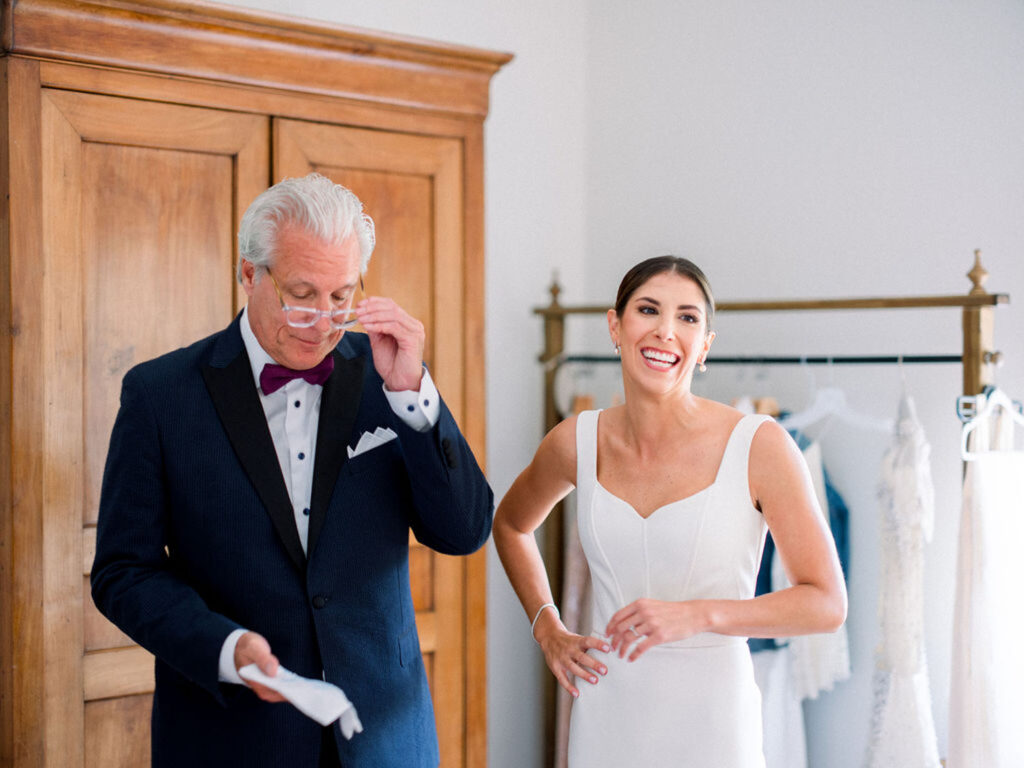 Father of the bride adjusting his glasses as the bride smiles