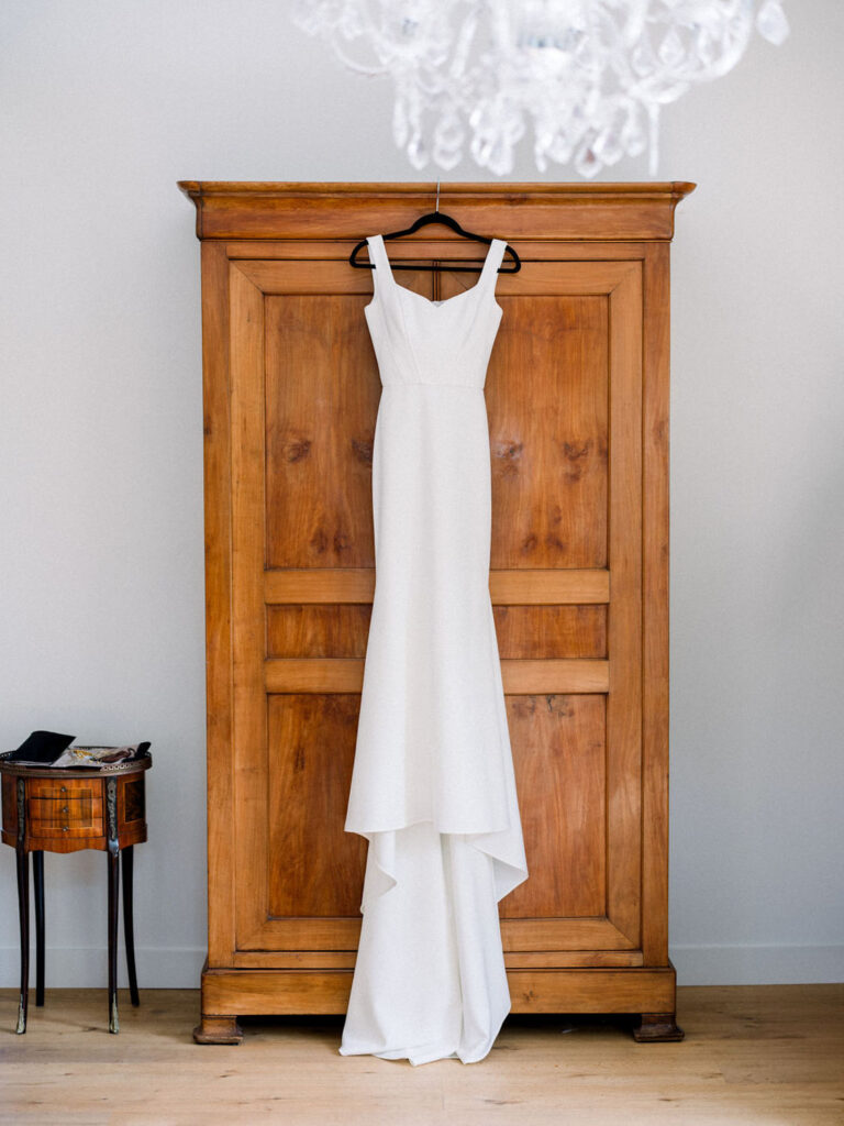 Bride’s wedding gown hanging elegantly on a wooden wardrobe