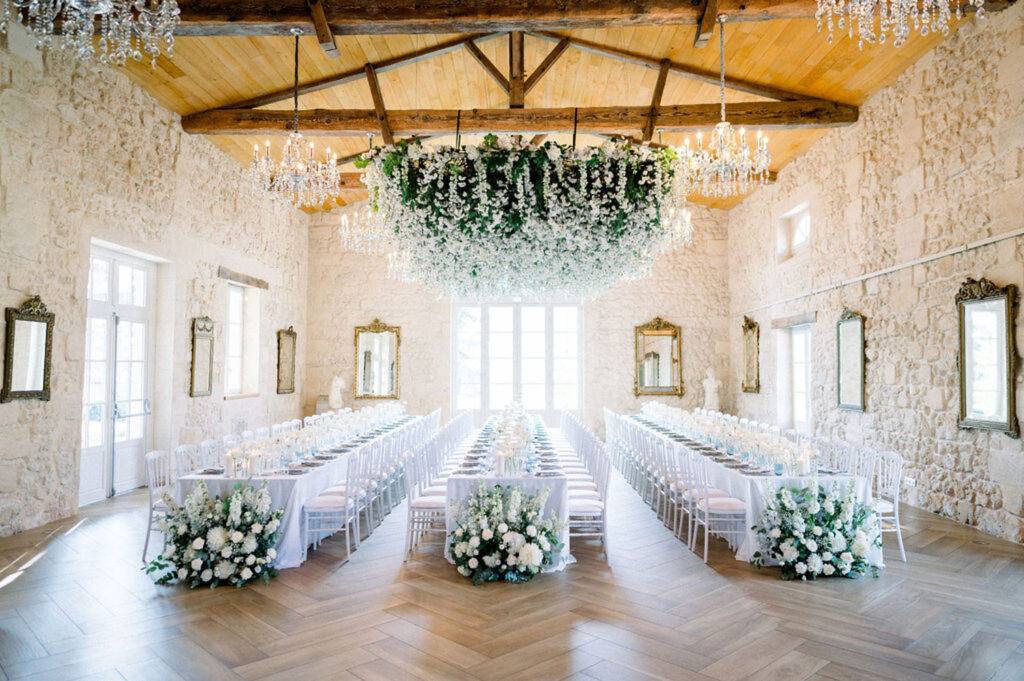 Elegant reception hall at Château Gassies with cascading floral chandeliers and long tables