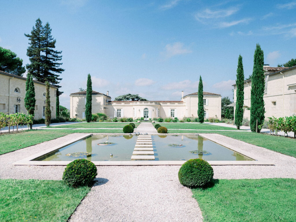 Château Gassies courtyard with a reflective pool and cypress trees