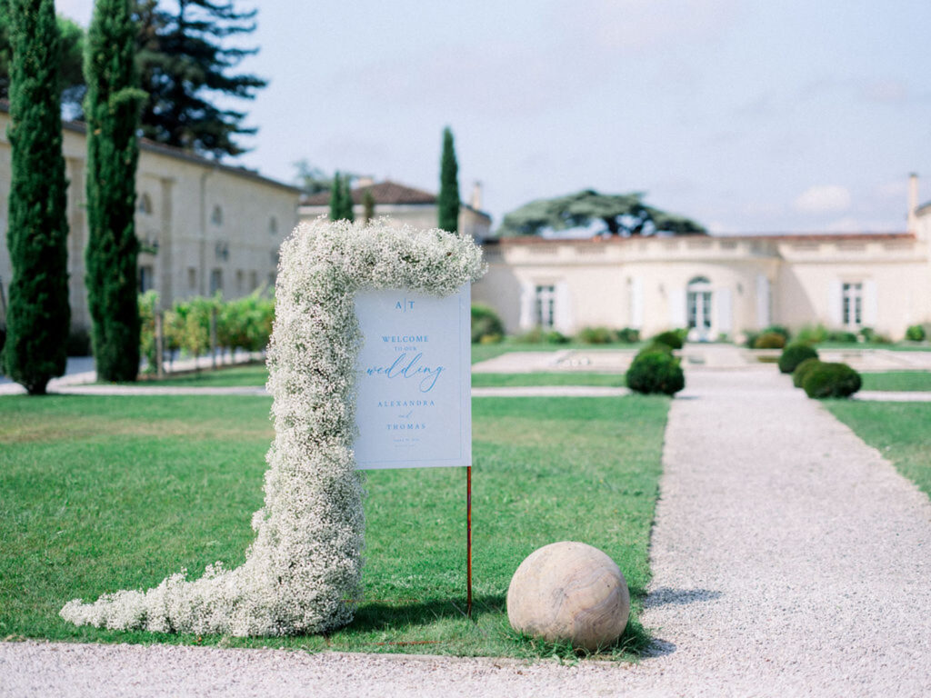 Elegant welcome sign with cascading floral arrangement at Château Gassies