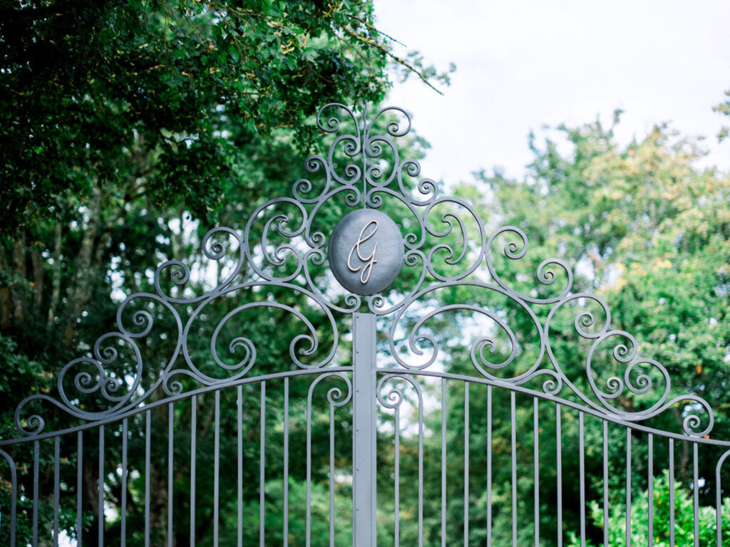 Intricate wrought iron gate with a "G" emblem at Château Gassies