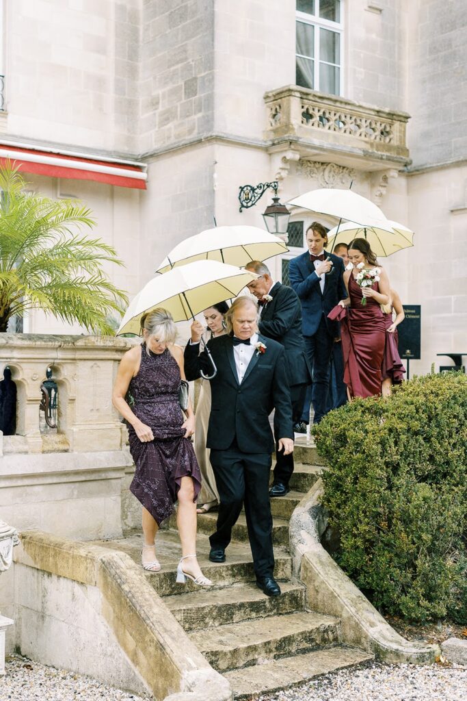 Wedding guests descending stairs with umbrellas