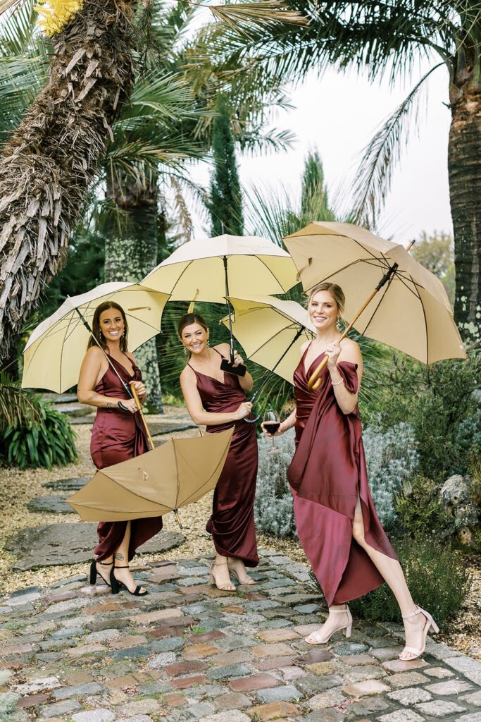 Bridesmaids cheerfully holding umbrellas on a rainy wedding day