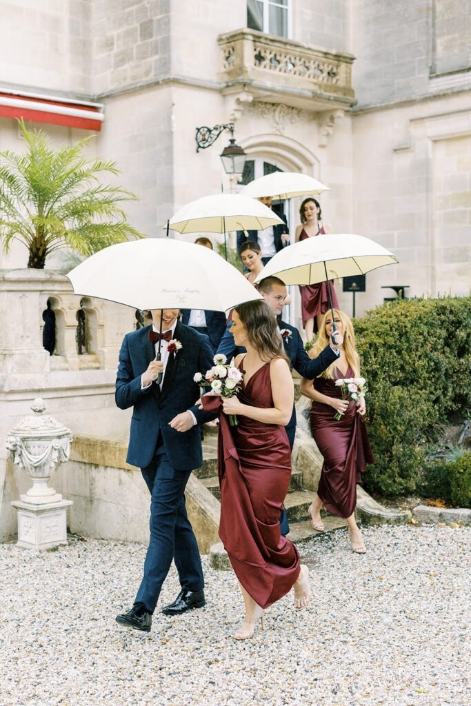 Wedding guests walking under umbrellas on a pebble pathway