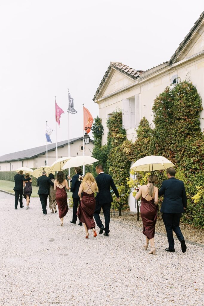 Wedding party under umbrellas walking through the venue's grounds