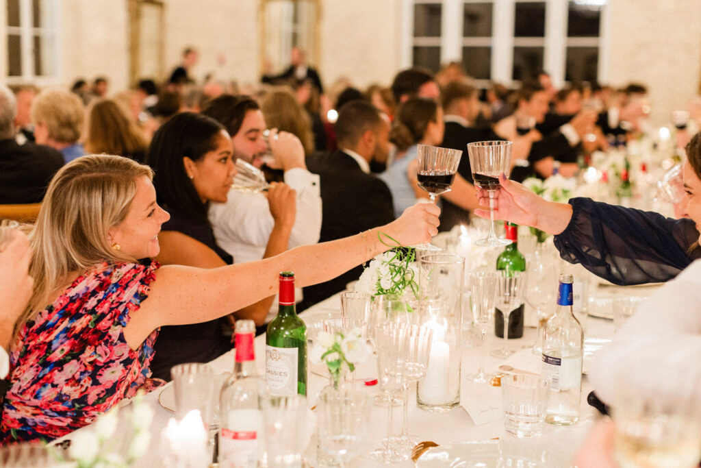 Guests raise glasses in a joyful toast during Lauren & Richie’s wedding party in Bordeaux