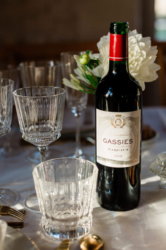 A rich bottle of Château Gassies Margaux wine sits on a candlelit table