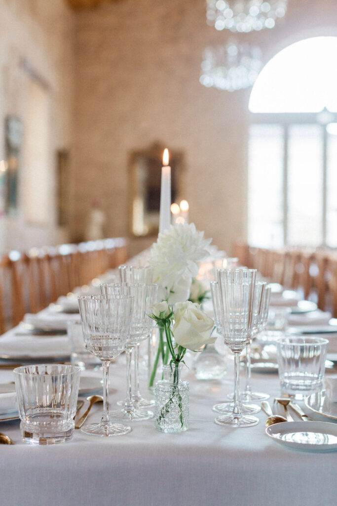 A close-up of the reception table adorned with crystal glassware, white florals, and elegant candlelight