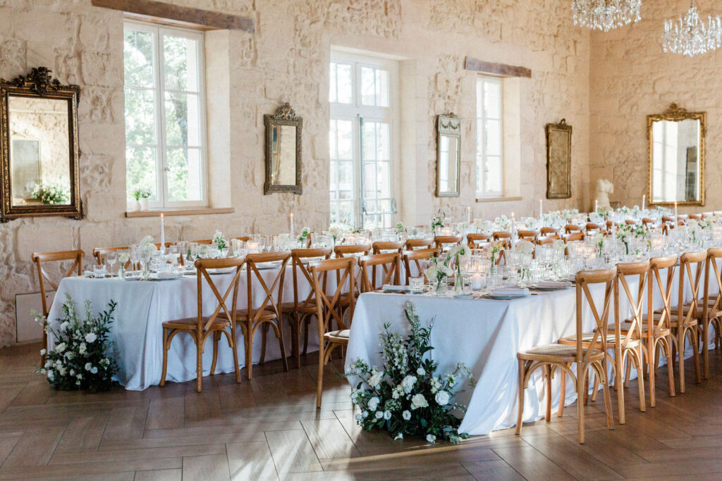 Elegant long tables adorned with white florals and candlelight, creating a romantic atmosphere for the Bordeaux wedding celebration