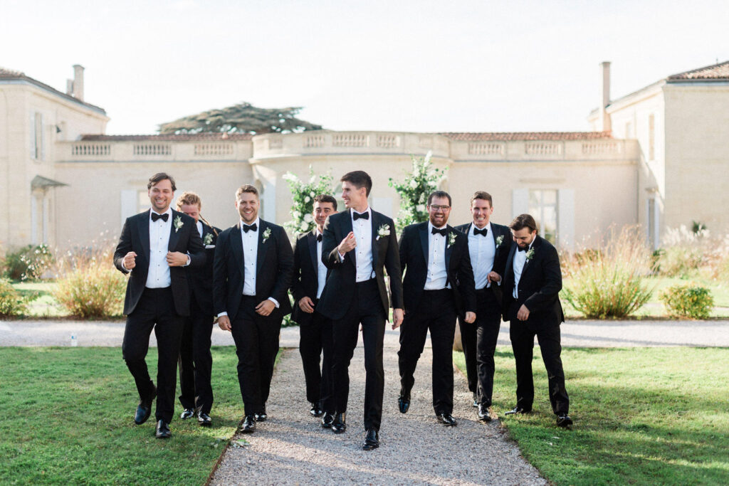 The groom and his groomsmen walk confidently through the grounds of the château