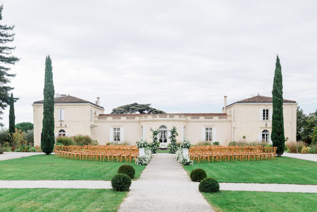 Outdoor wedding ceremony setup featuring wooden chairs and lush floral arrangements for a wedding party in Bordeaux