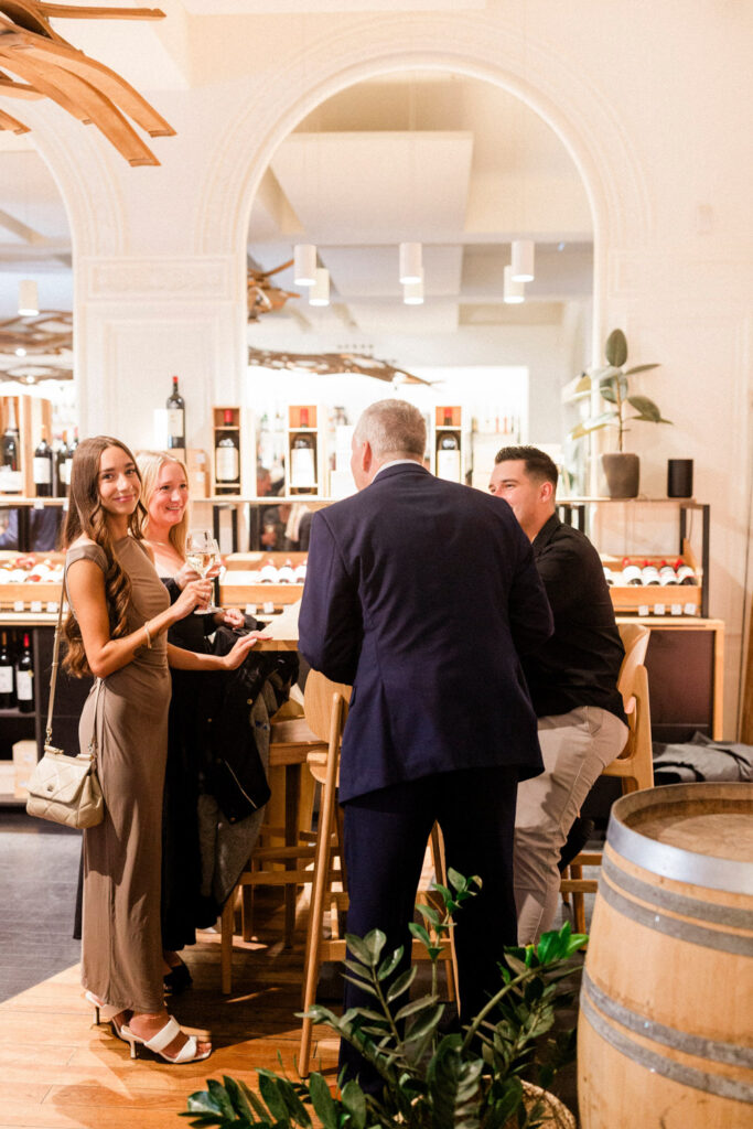 Guests mingling at a chic wine bar, enjoying pre-wedding party in Bordeaux.