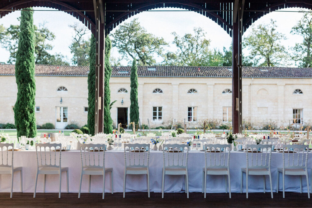 A grand welcome party setup under an open-air pavilion, framed by towering cypress trees