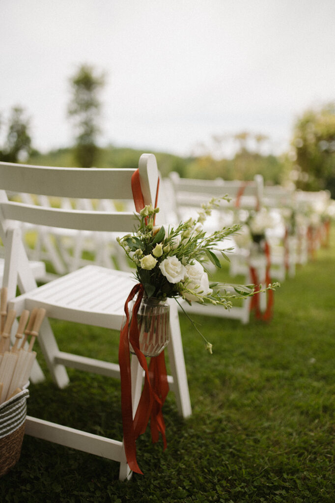 Aisle chairs decorated with flowers and ribbon.