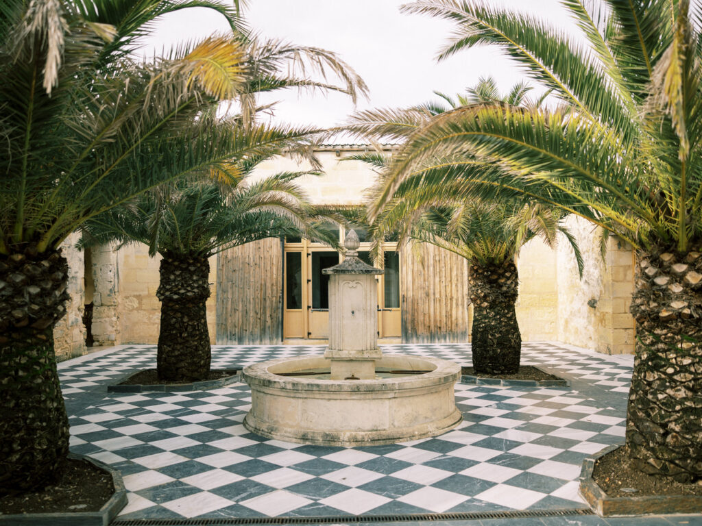 Courtyard with palm trees and checkerboard flooring at a French château.