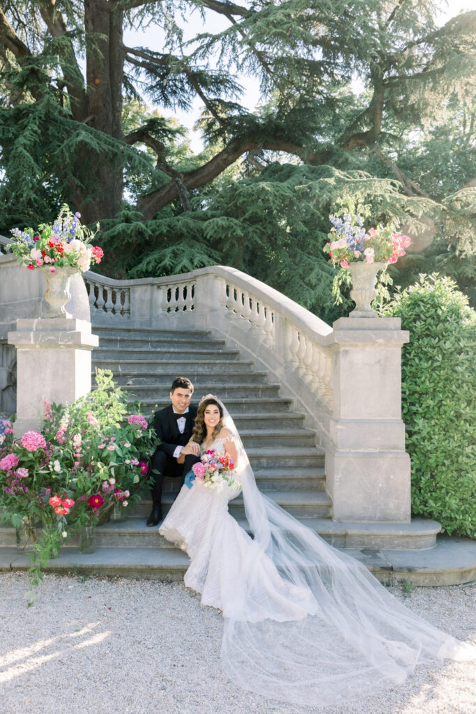 Elegant couple sitting on stone steps with floral arrangements