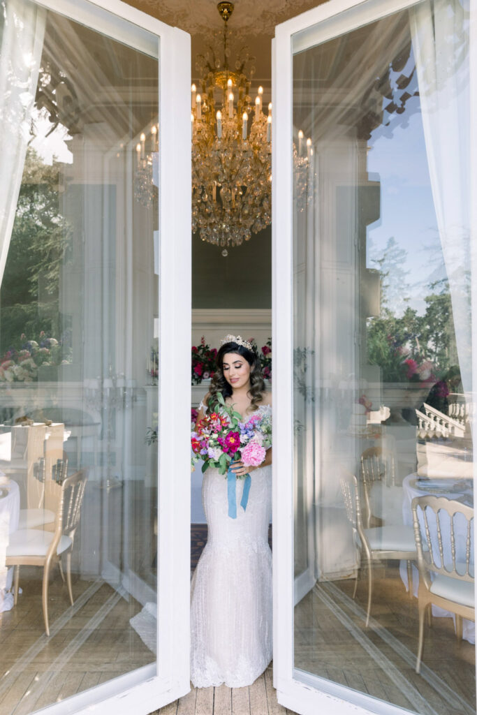 Bride standing in grand doorway with floral bouquet