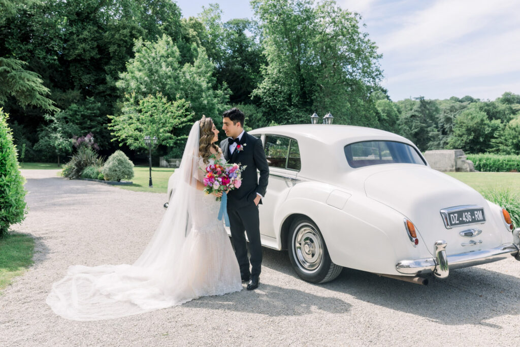 Couple embracing beside a vintage car in a French château garden