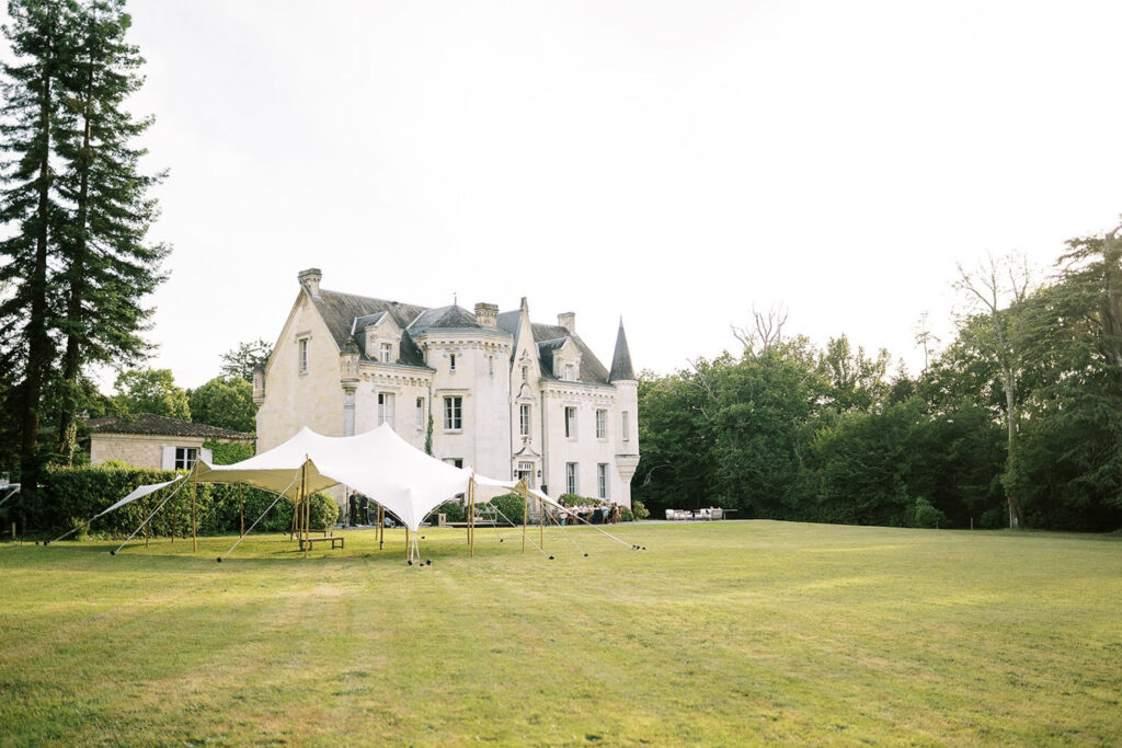 Tented outdoor setup beside an elegant European castle.