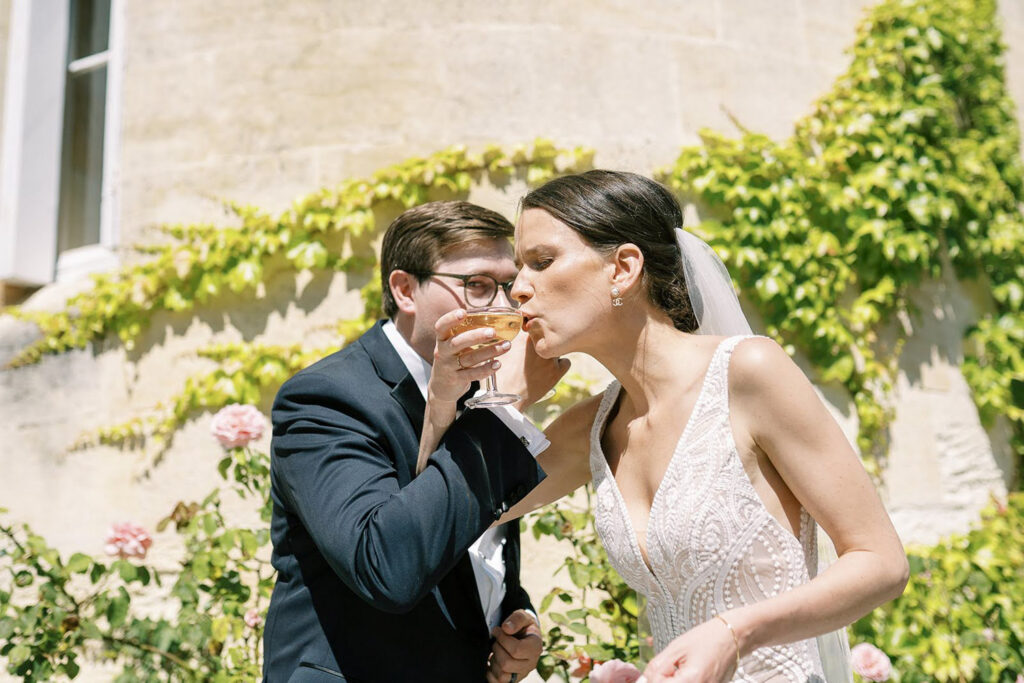 Newlyweds share a celebratory toast surrounded by blooming garden roses.