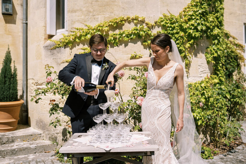 Couple pouring champagne tower in a romantic courtyard at their destination wedding.