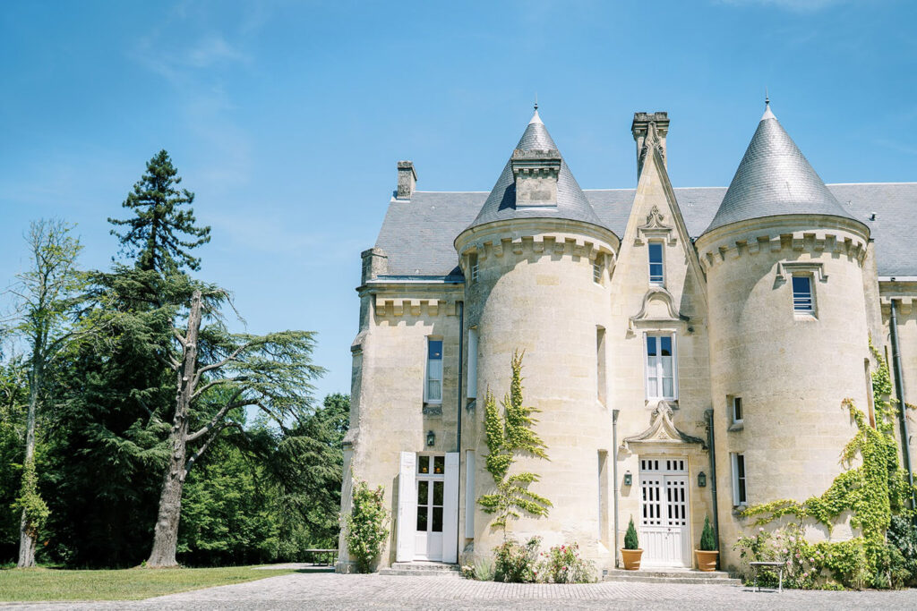 Scenic view of French chateau architecture with blue sky and lush greenery.