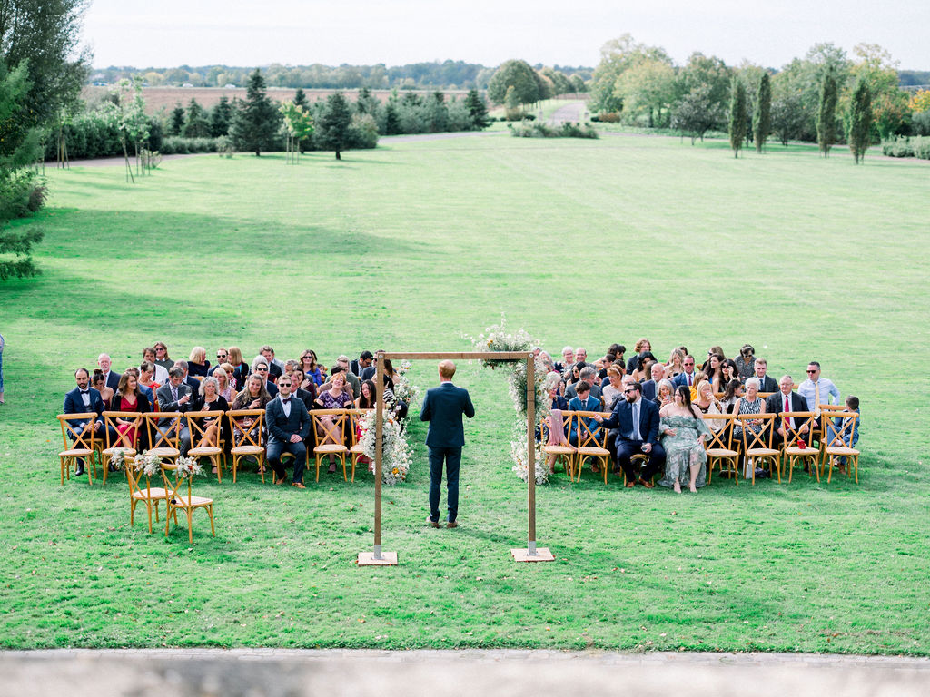 Guests seated on lawn for outdoor ceremony with expansive green views