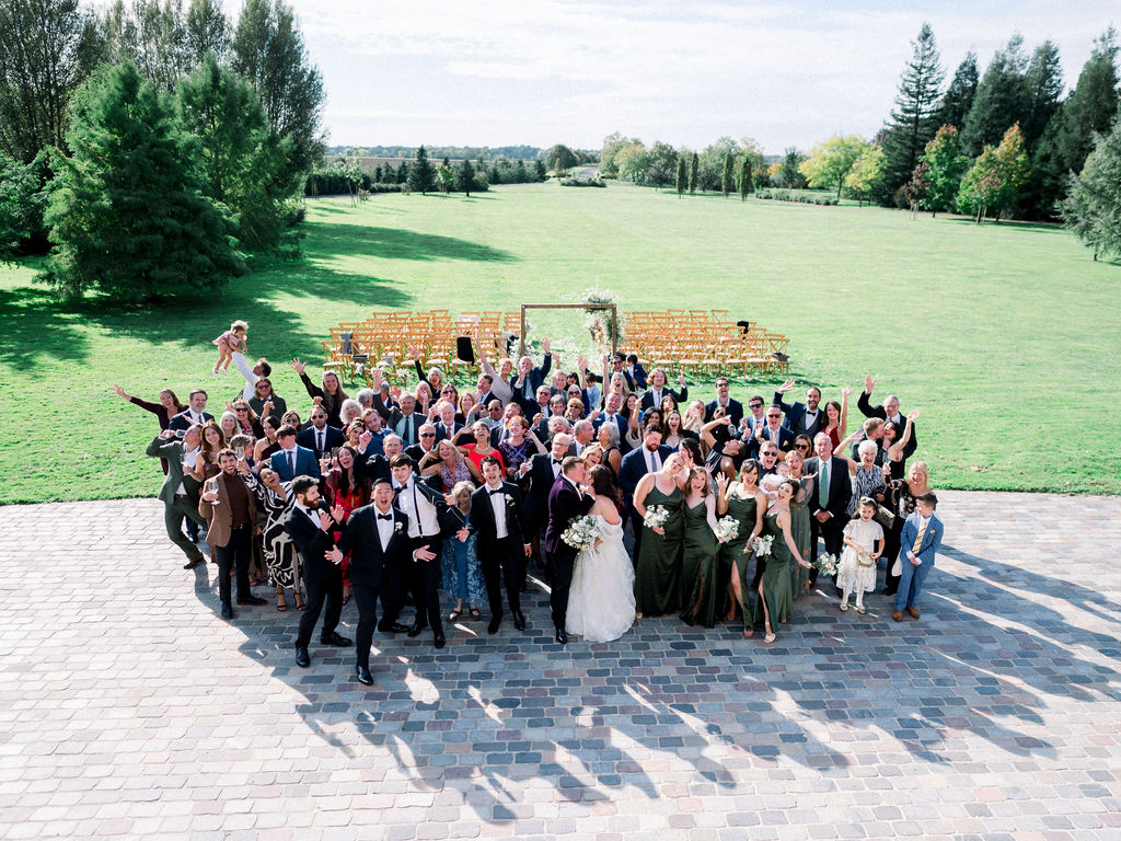 Joyful group shot of all guests outside the château after the ceremony