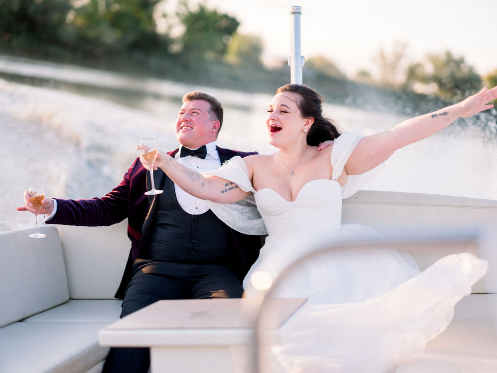 Couple laughing and celebrating with champagne while cruising on a boat
