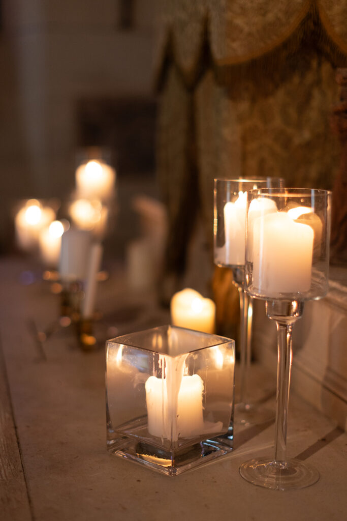 A glowing candle display flickers gently on a stone mantle.